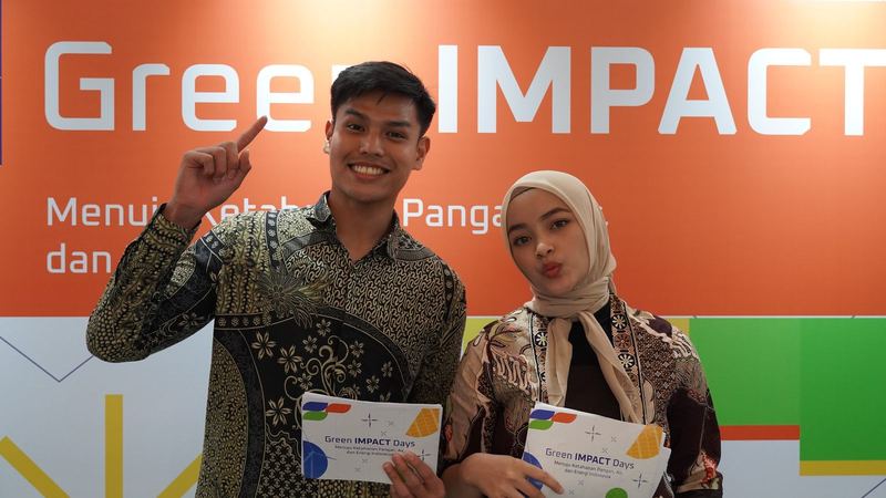 Dua peserta memegang sertifikat di depan latar Green Impact Days 2024